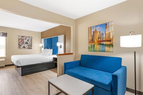 a hotel room with a bed and a blue couch at Best Western Forsyth-Decatur in Forsyth