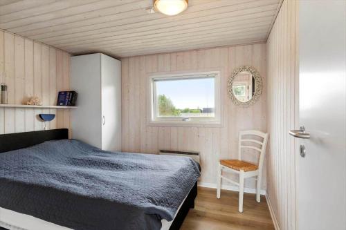 a bedroom with a bed and a window and a chair at 402-Harboore-Flyvholmvej-23 in Harboør