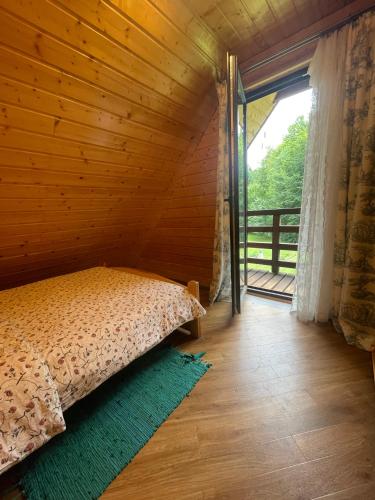 a bed in a wooden room with a large window at Gawra Werlas in Werlas
