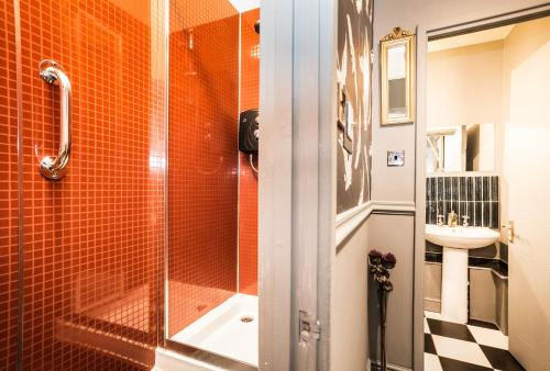 a bathroom with an orange tiled shower and a sink at Daiches Braes Brunstane Portobello in Edinburgh
