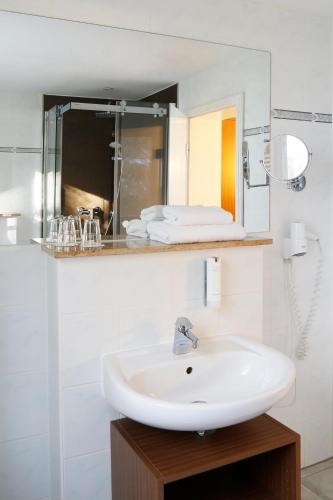 a white bathroom with a sink and a mirror at Springbach-Mühle Belzig in Bad Belzig