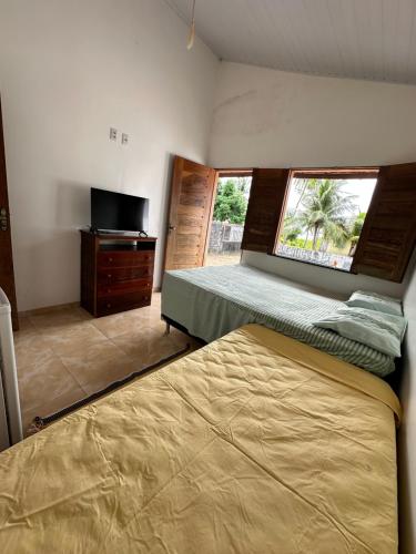 a bedroom with two beds and a tv and a window at Nosso Chalé in Marapanim