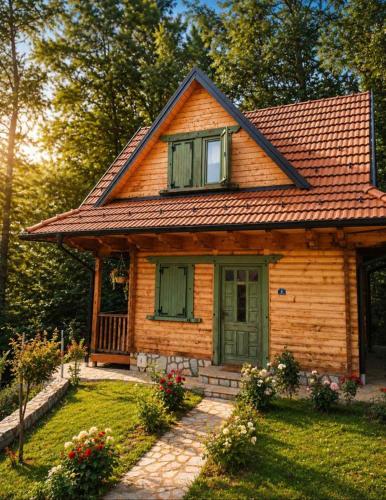 a small wooden house with green doors and flowers at STD Bešević "Naše Brdo" Ivanjica in Ivanjica
