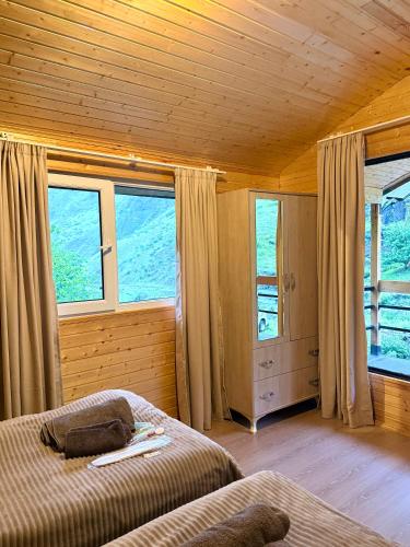 a bedroom with a bed and windows in a cabin at Guesthouse Shete in Khonischala