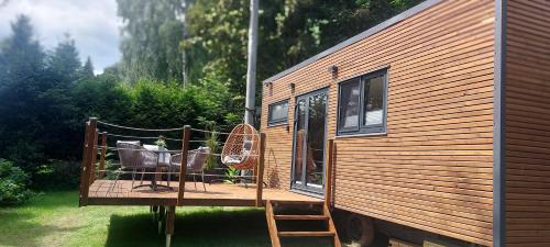 a house with a porch with a chair and a table at Tiny house U Lasiček in Perštejn