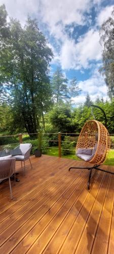 a wooden deck with a rattan chair and tables at Tiny house U Lasiček in Perštejn