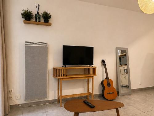 a living room with a flat screen tv and a guitar at Charmant studio,Terrasse et Parking in Montpellier