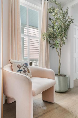 a white chair in a living room with a plant at Downtown CHS King Beds Convert to Singles in Charleston