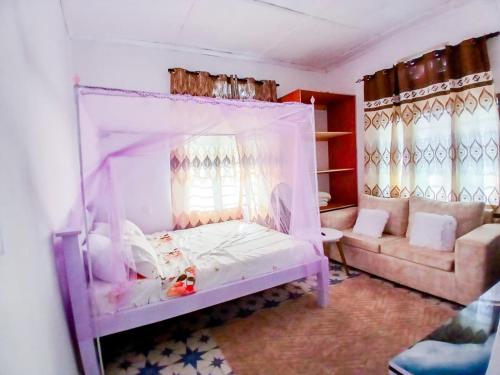 a bedroom with a canopy bed and a couch at Diamond luxury Studio Watamu in Watamu