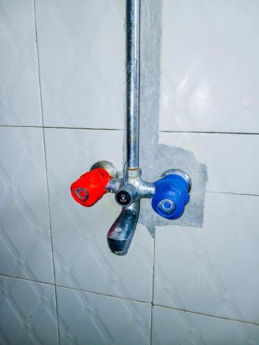 a shower nozzle with two different colored faucets at Diamond luxury Studio Watamu in Watamu