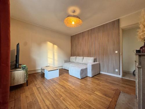 a living room with a couch and a television at L'Echappée Belle in Paray-le-Monial