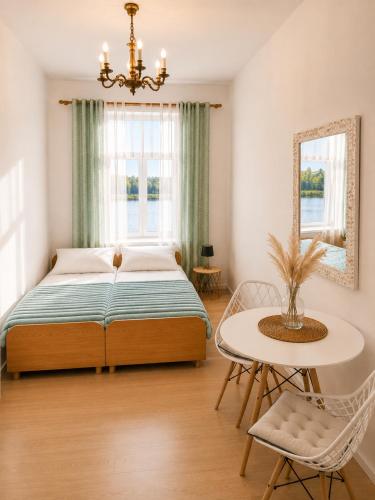 ein Schlafzimmer mit einem Bett, einem Tisch und einem Fenster in der Unterkunft Sentane in Swiętajno