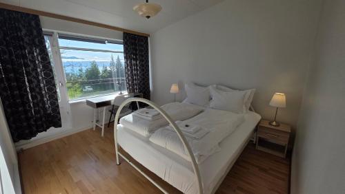 a white bed in a room with a window at Húsavík Apartment in Húsavík