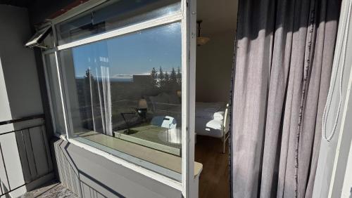 a window on a balcony with a view of a bathroom at Húsavík Apartment in Húsavík