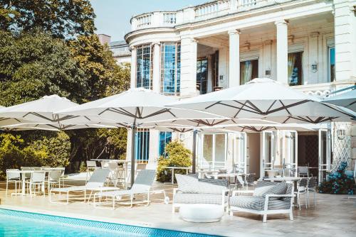 - une piscine avec des chaises et des parasols à côté d'un bâtiment dans l'établissement La Villa Guy & Spa - Teritoria, à Béziers