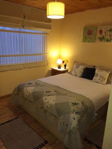 a bedroom with a bed and a window and a lamp at Casa punta de lobos in Pichilemu