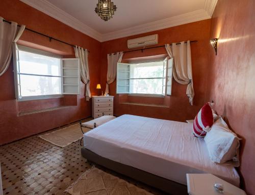 a bedroom with a bed and two windows at Villa Dar Luz in Marrakesh