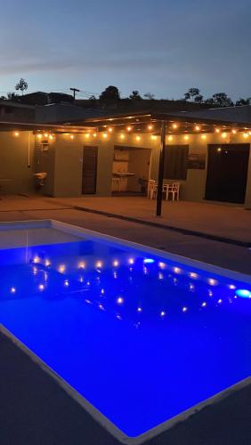 a swimming pool lit up at night with lights at Espaço Mattigor, Chácara mil m2, piscina grande com prainha e vista deslumbrante in Caçapava