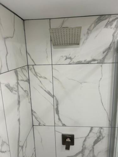 a white tiled bathroom with a shower with a vent at Where Comfort Meets Cozy Vibes in Montreal