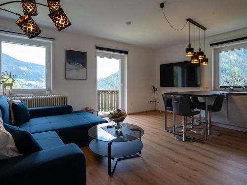 a living room with a blue couch and a table at RABENSTEINER - Panorama Apartments - Bad Kleinkirchheim in Bad Kleinkirchheim