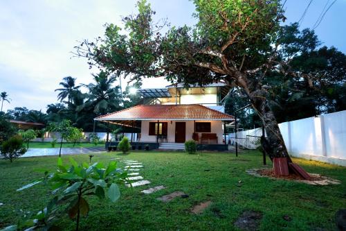a small house with a tree in the yard at MeadowView Cottage Marari in Mararikulam