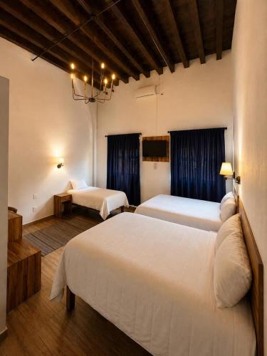 a hotel room with two beds and blue curtains at Palacio de las Rosas in Durango