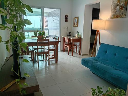 a living room with a blue couch and a table at Piscina aquecida e varanda, dois quartos com ar condicionado in Aracaju