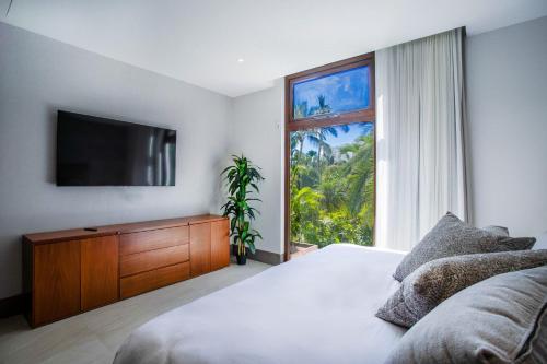 a bedroom with a bed and a tv and a window at Quiya Beach Residences in Cruz de Huanacaxtle