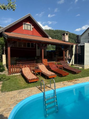 a pool with benches and a house with a red building at Vikendica Andrija Drina in Gvozdačko Polje