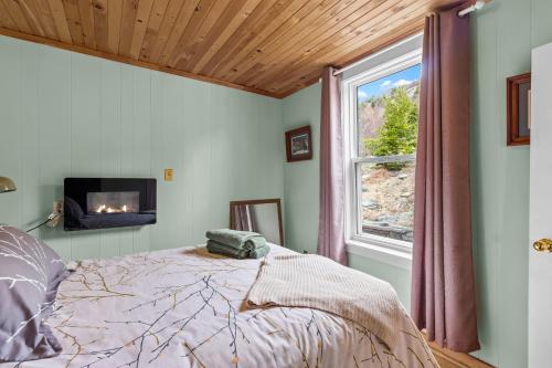a bedroom with a bed with a fireplace and a window at Brigus Cottage Parking, Fire Pit & Garden in Brigus