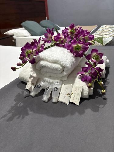 a bouquet of purple flowers and towels on a bed at Weng Kong Hotel in Slim River