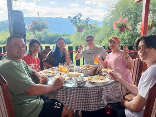 a group of people sitting around a table eating food at PROKLETIJE COTTAGES in Plav