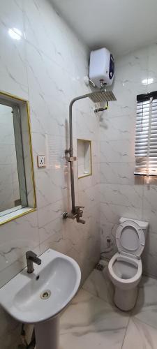 a white bathroom with a toilet and a sink at Kiarra Suites Owerri in Owerri