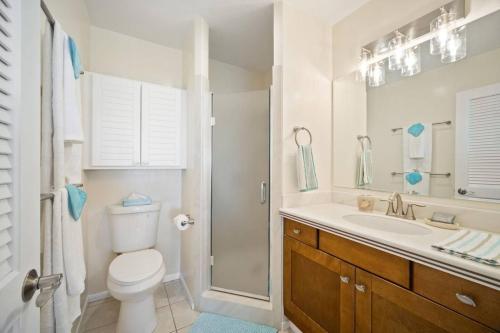 a white bathroom with a toilet and a sink at Makai Dream (Oceanfront) in Lihue