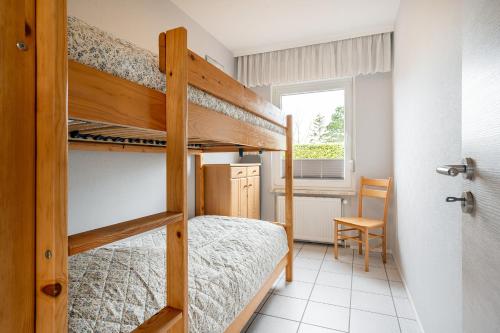 a bedroom with two bunk beds and a chair at Bungalow Windstille in Norddeich