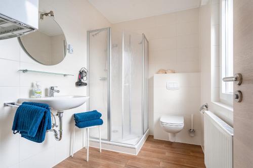 a white bathroom with a sink and a toilet at Bungalow Windstille in Norddeich