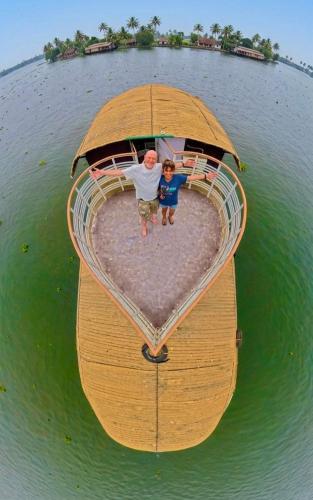 a man and a boy standing on a boat in the water at Navora Houseboats in Alleppey