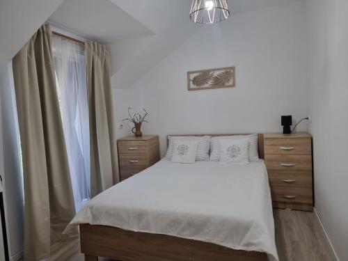 a bedroom with a white bed and a window at Cozy Lake House in Cinciş