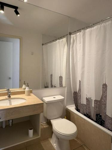a bathroom with a toilet and a sink and a shower curtain at Laguna Bahia Velero in Algarrobo