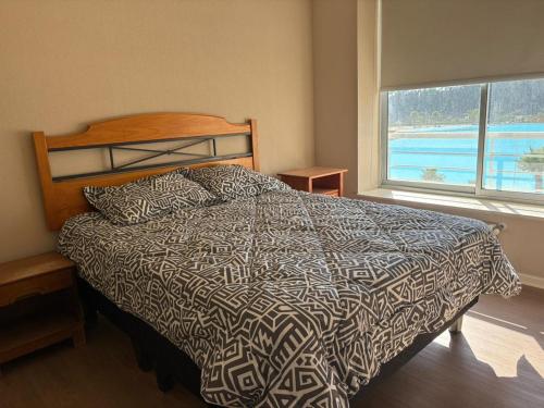 a bedroom with a bed and a large window at Laguna Bahia Velero in Algarrobo