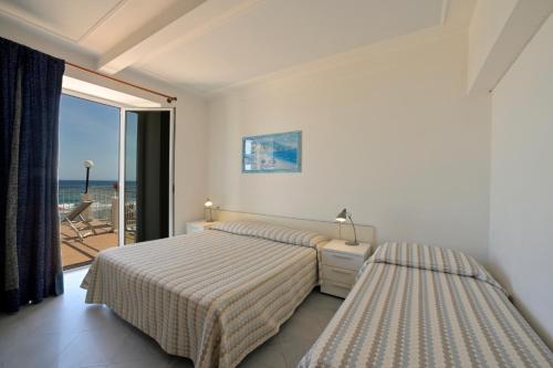 two beds in a bedroom with a view of the ocean at Hotel La Balnearia in Alassio