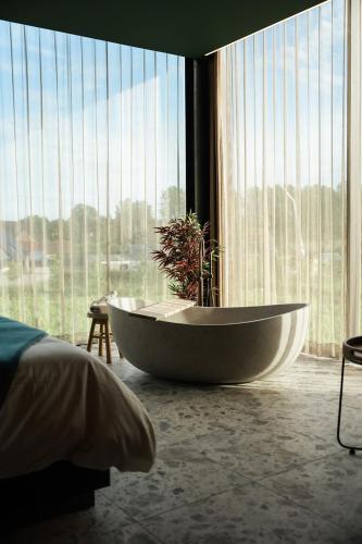 a bath tub in a room with a large window at Wijndomein Leine in Opwijk