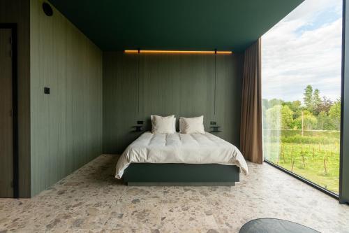 a bedroom with a bed and a large window at Wijndomein Leine in Opwijk