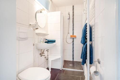 a white bathroom with a toilet and a sink at Bungalow Hohes Riff in Norddeich