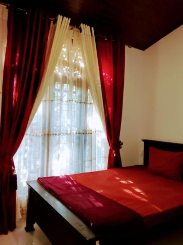 a bedroom with a bed with red curtains and a window at Luuna'S Hostel Sigiriya in Sigiriya