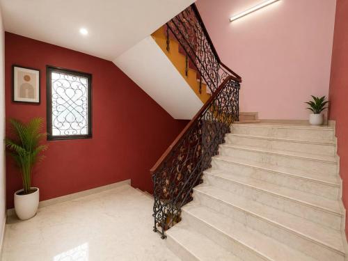 a staircase in a home with red walls and a window at Hotel Bypass in Madurai