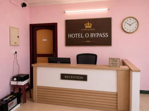 a hotel reception desk with a clock on the wall at Hotel Bypass in Madurai