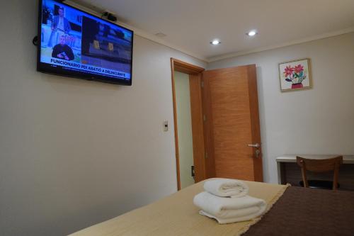 a room with towels on a bed with a tv on the wall at Hotel D&V Concepción in Concepción