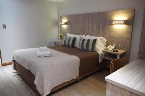 a hotel room with a large bed and a table at Hotel D&V Concepción in Concepción