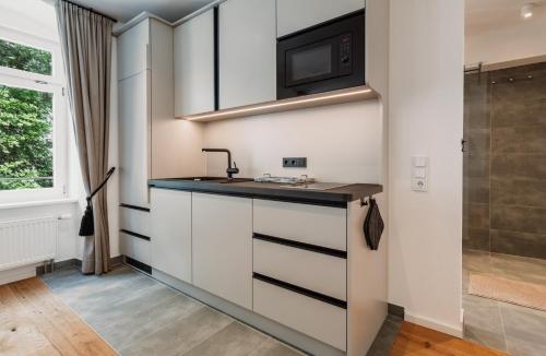 a kitchen with white cabinets and a sink and a microwave at Schloss am Bodensee I Private Sauna & Whirlpool in Stockach